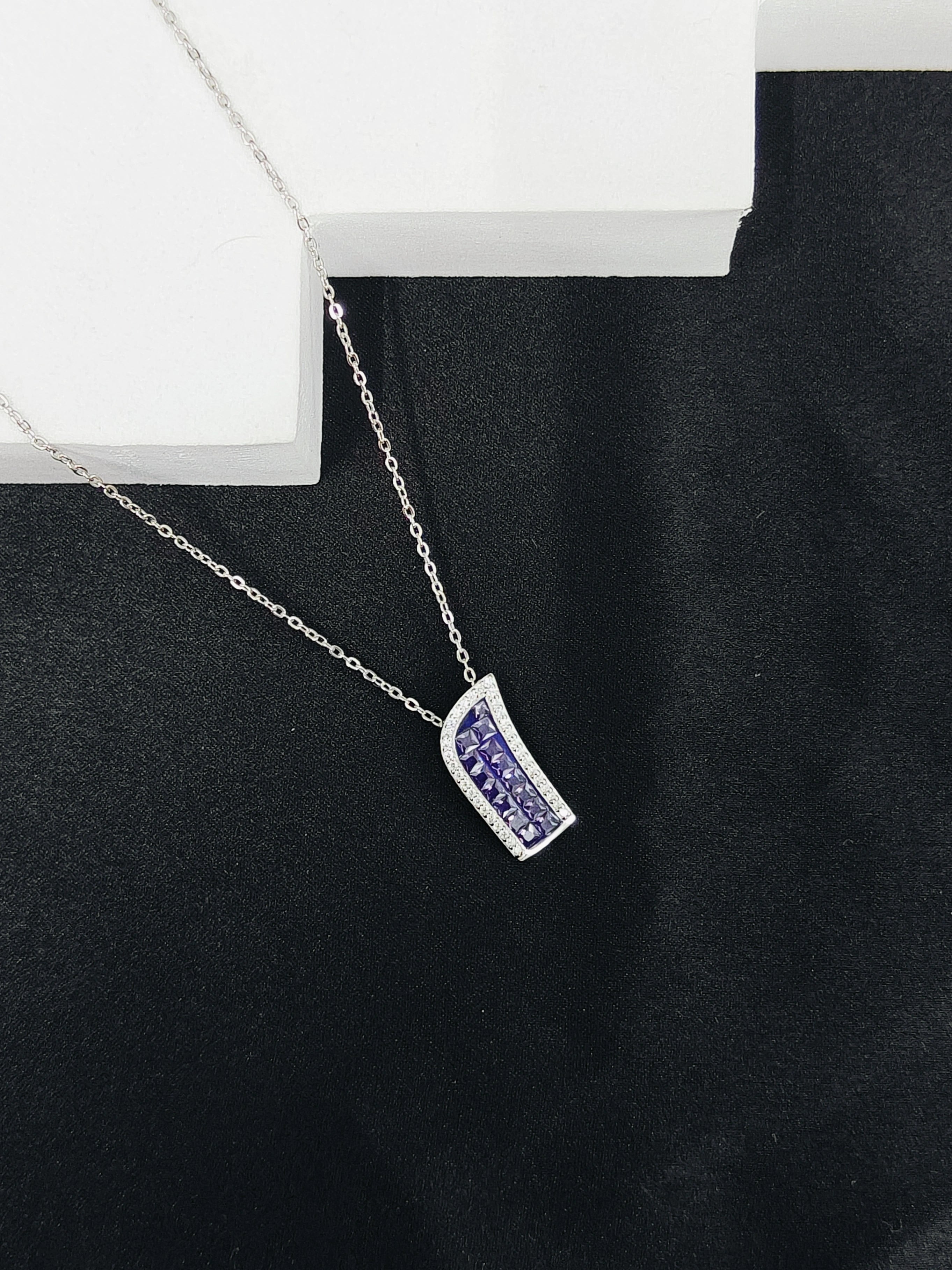 Silver necklace with a purple pendant on a black background